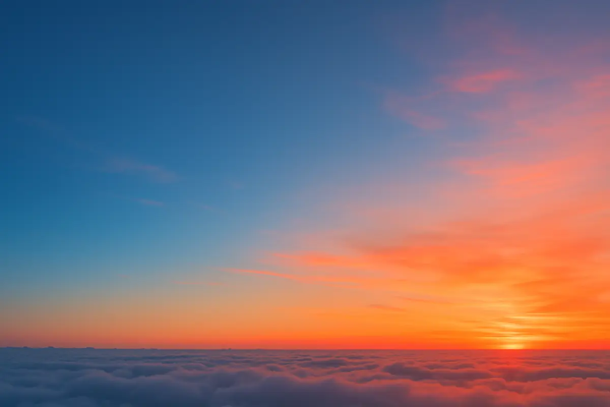 A realistic scene showing a bright blue sky fading to a warm red-orange sunset over calm clouds, illustrating Rayleigh scattering of light.